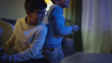 Dos-Niños-Pequeños-En-Casa-Divirtiéndose-Jugando-Con-La-Consola-De-Juegos-De-Computadora-En-La-Televisión-Peleando-Por-Los-Controladores-A-Altas-Horas-De-La-Noche-3